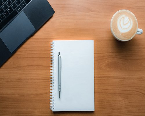 A cup of coffee and a notebook on a wooden table